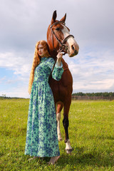 Fototapeta premium orange hair woman and her brown horse in the field just relaxing in summer day