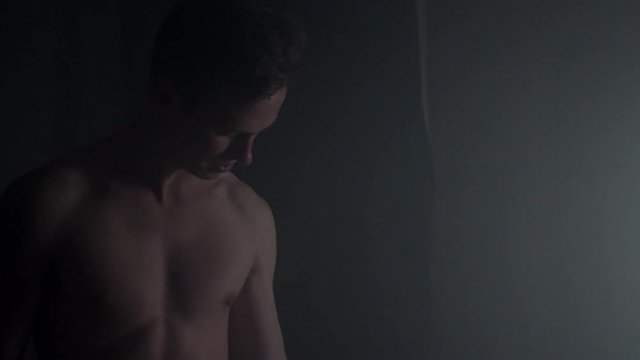 Young guy with athletic body and abs lifting and training with dumbbells.