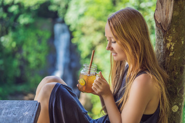 Closeup portrait image of a beautiful woman drinking ice tea with feeling happy in green nature and...