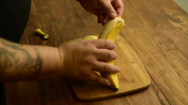 pelando pl&aacute;tano banana con las manos quitando la piel