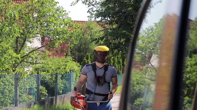 Slow Motion Of A Landscaper Walking Towards Camera With A Weed Trimmer