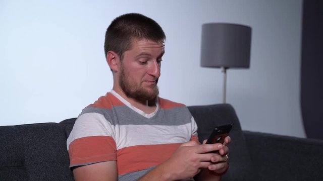 Zoom out of Caucasian Male on Cellphone on Couch typing frantically