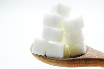 Sugar sweet cubes high calories in wooden spoon : fat diet healthy food concept.