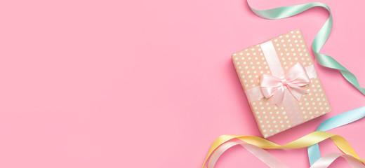 Gift or present box with beautiful festive ribbon on pink background top view. Flat lay composition for celebration, holiday, birthday, Valentine's Day, March 8, mother day, wedding. Congratulation