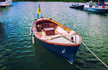 Fototapeta na wymiar Classic traditional wooden boat on the water with Swedish flag