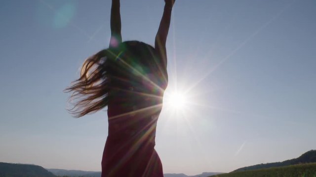 a woman jumping in the air in front of the sun