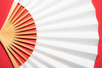whtie Japanese foldable fan on red background with copy space