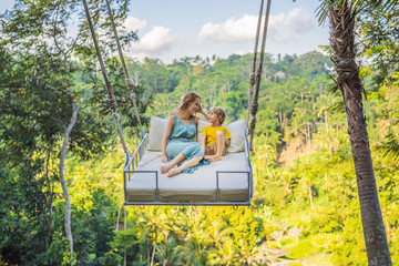 Mother and son swinging in the jungle rainforest of Bali island, Indonesia. Swing in the tropics....
