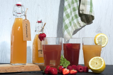 erfrischendes komboucha in flasche und glas mit erdbeeren himbeeren zitrone melisse und eiswürfel...