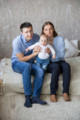 Happy Young Caucasian Family Sitting on Bed