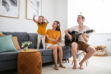 dad plays guitar, mom and girl with Down syndrome