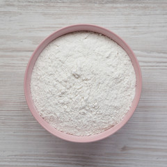 Gluten free rice flour in a pink bowl over white wooden surface, top view. Flat lay, overhead, from above. Close-up.