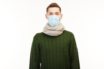 Man in a green sweater wears medical mask.