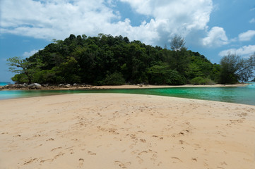 Tropical beach coastline with cloudy blue sky..Beach on mainland and small island seperated by emerald sea canal at layan beach seashore with crowded bare footprint.