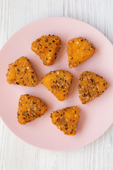 Fried camembert on a pink plate on a white wooden surface, overhead view. Flat lay, top view, from above.