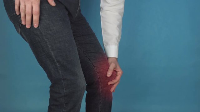 Male office worker holding red sore knee arthrosis and arthritis concept, office diseases, gonarthrosis