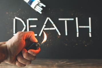 Death sign from cigarettes. Dangerous habit. Harmful for health. Man holds lighter in hands.