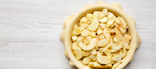 Preparation of apple pie on a white wooden table, top view. Flat lay, overhead, from above. Copy space.