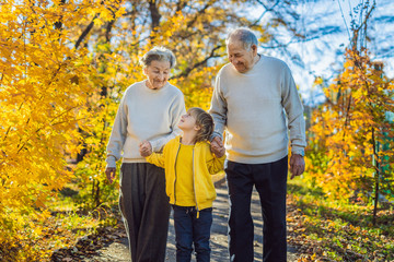 Senior couple with baby grandson in the autumn park. Great-grandmother, great-grandfather and great-grandson