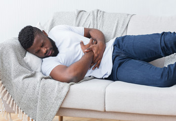 Black man suffering from stomach ache at home