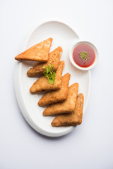 crispy Potato triangles or batata vada covered with bread crumbs and then deep fried. served with tomato ketchup. selective focus