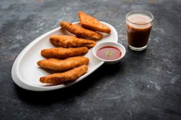 crispy Potato triangles or batata vada covered with bread crumbs and then deep fried. served with tomato ketchup. selective focus