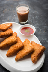 crispy Potato triangles or batata vada covered with bread crumbs and then deep fried. served with tomato ketchup. selective focus