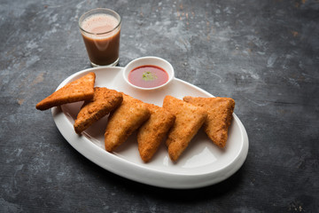 crispy Potato triangles or batata vada covered with bread crumbs and then deep fried. served with tomato ketchup. selective focus