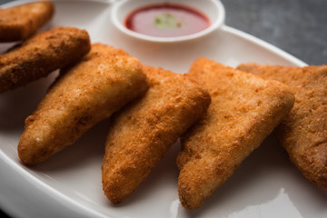 crispy Potato triangles or batata vada covered with bread crumbs and then deep fried. served with tomato ketchup. selective focus