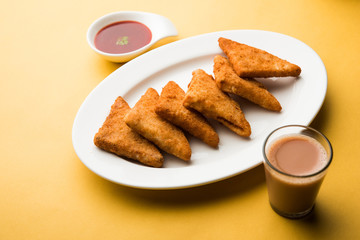 crispy Potato triangles or batata vada covered with bread crumbs and then deep fried. served with tomato ketchup. selective focus