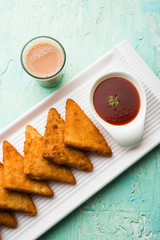 crispy Potato triangles or batata vada covered with bread crumbs and then deep fried. served with tomato ketchup. selective focus