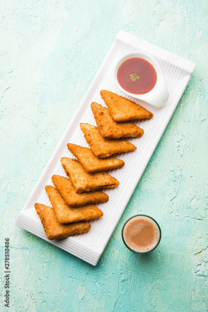 Poster crispy Potato triangles or batata vada covered with bread crumbs and then deep fried. served with tomato ketchup. selective focus