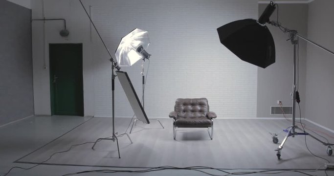 Photo studio with leather chair, c-stand, bouncing desk and octabox / moving shot