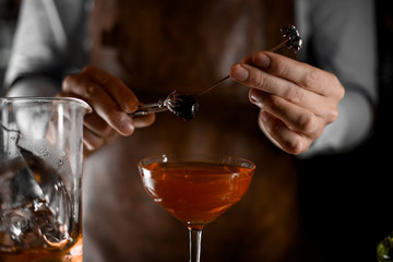Bartender putting berry on the skewer with tweezers