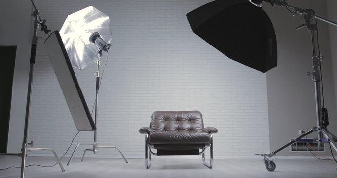 Photo studio with leather chair, c-stand, bouncing desk and octabox / moving shot