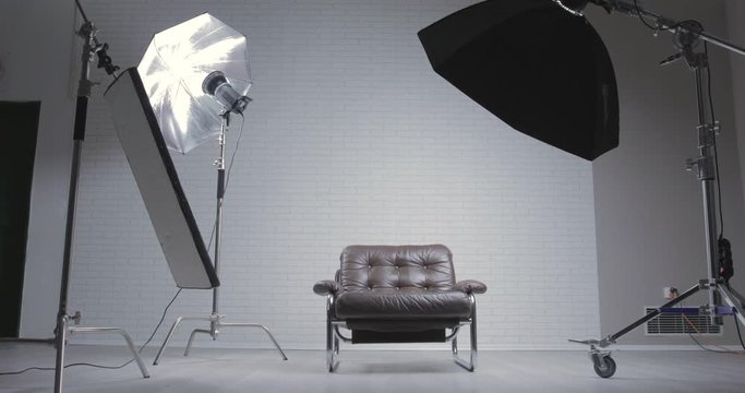 Photo studio with leather chair, c-stand, bouncing desk and octabox / moving shot