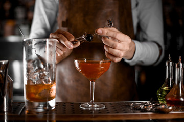 Male bartender putting berry on the skewer with tweezers