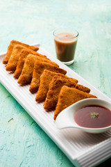 crispy Potato triangles or batata vada covered with bread crumbs and then deep fried. served with tomato ketchup. selective focus