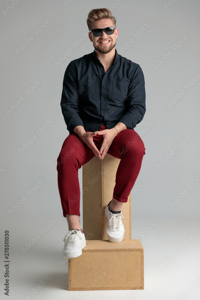 Wall mural Cheerful casual man laughing on a throne made of boxes