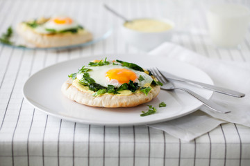 Healthy homemade breakfast or brunch (quick meal)-spiced fried eggs with Indian spices and sauteed spinach used to top toasted pitas spread with turmeric yogurt on white plate.Horizontal orientation.
