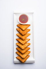 crispy Potato triangles or batata vada covered with bread crumbs and then deep fried. served with tomato ketchup. selective focus