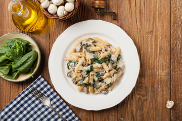 Penne pasta with spinach and mushrooms. Sprinkled with cheese.