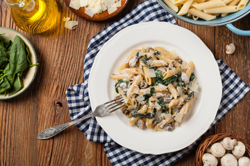 Penne pasta with spinach and mushrooms. Sprinkled with cheese.