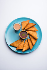 crispy Potato triangles or batata vada covered with bread crumbs and then deep fried. served with tomato ketchup. selective focus