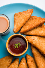 crispy Potato triangles or batata vada covered with bread crumbs and then deep fried. served with tomato ketchup. selective focus