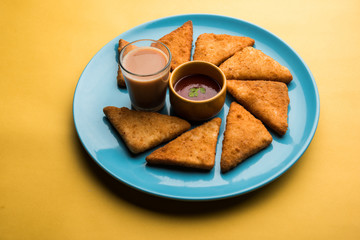 crispy Potato triangles or batata vada covered with bread crumbs and then deep fried. served with tomato ketchup. selective focus
