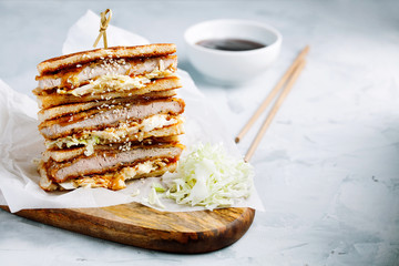 Katsu Sando - traditional japanese cutlet sandwich with deep fried pork,cabbage,japanese mayonnaise and tonkatsu sauce on a light background close-up with copy space for text.Japanese fast food