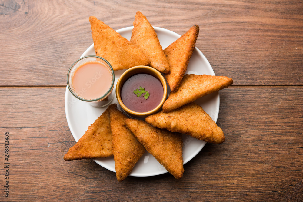 Poster crispy Potato triangles or batata vada covered with bread crumbs and then deep fried. served with tomato ketchup. selective focus