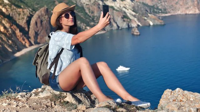Attractive young travel woman taking selfie using smartphone posing at seascape background