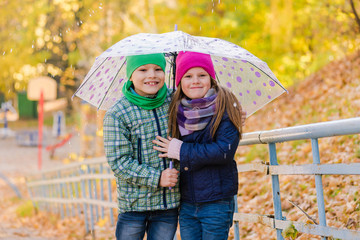 Two kids during autumn rain with umbrella